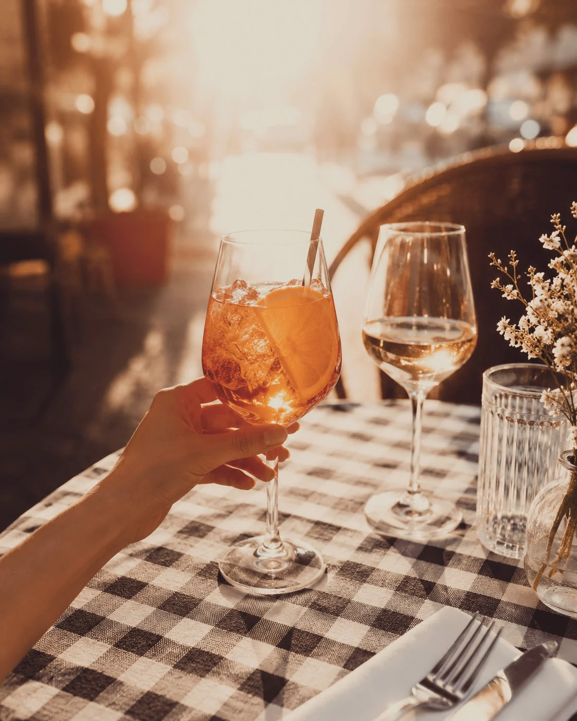 Aperol Spritz und Weisswein auf einem Tisch mit blau-weiss karierter Decke im Aussenbereich des Ristorante Arlecchino