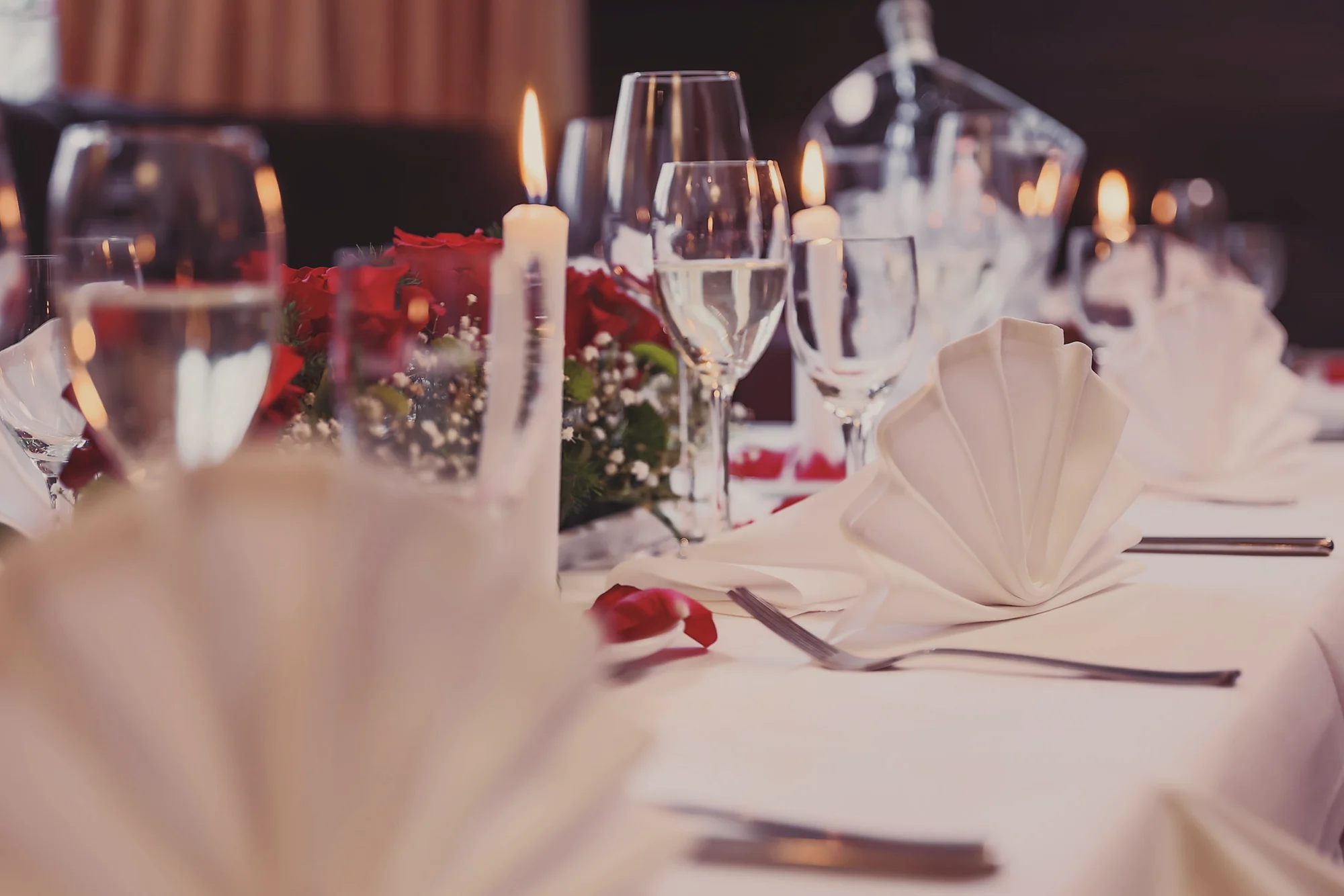 Festlich gedeckte Tafel mit Kerzen, Rosen und gefalteten Servietten
